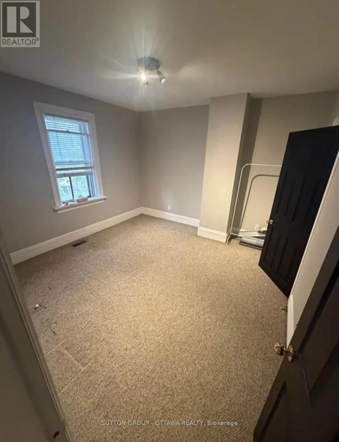 A room with a carpeted floor and a window.