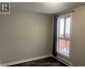A room with a window and a view of a red building outside.