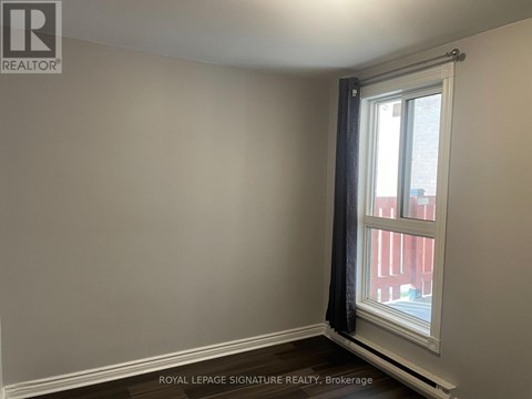A room with a window and a view of a red building outside.