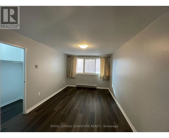 A room with wooden floors and a window with curtains.