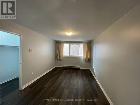A room with wooden floors and a window with curtains.