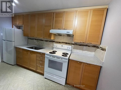 A kitchen with wooden cabinets and a white stove top oven.