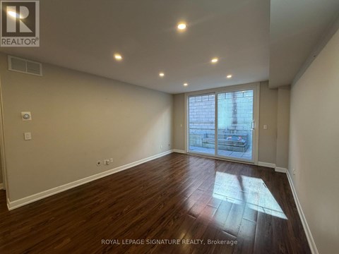 A room with wooden flooring and a sliding glass door.