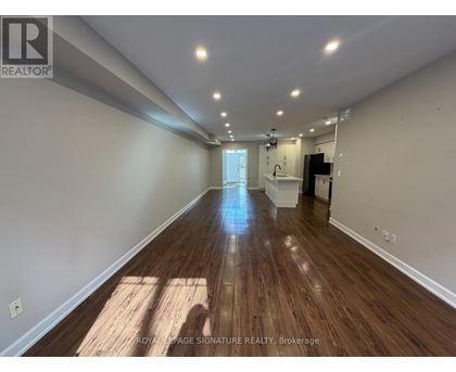A long, empty hallway with wooden floors and white walls.