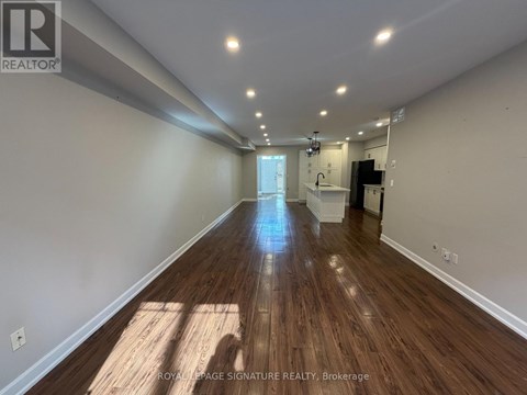 A long, empty hallway with wooden floors and white walls.