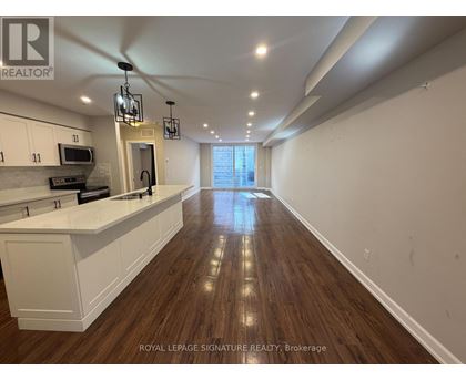 A well-lit kitchen with white cabinets and a wooden floor.