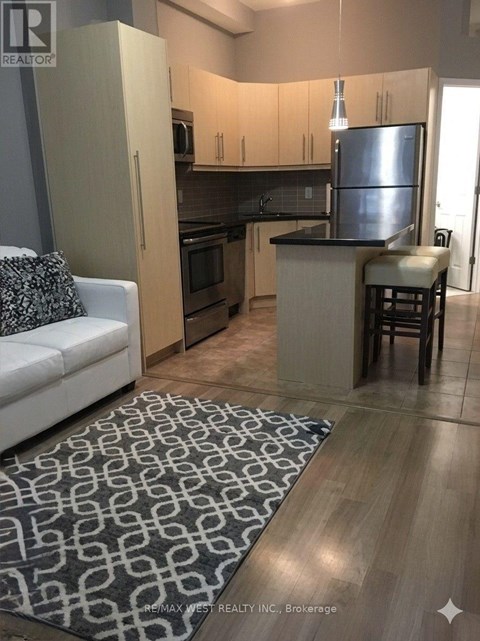 A kitchen with a refrigerator, microwave, and oven.