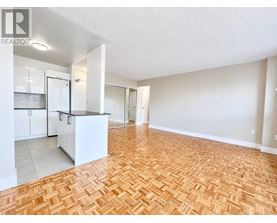 A spacious living room with hardwood flooring and white walls.