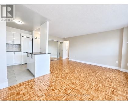 A spacious living room with hardwood flooring and white walls.