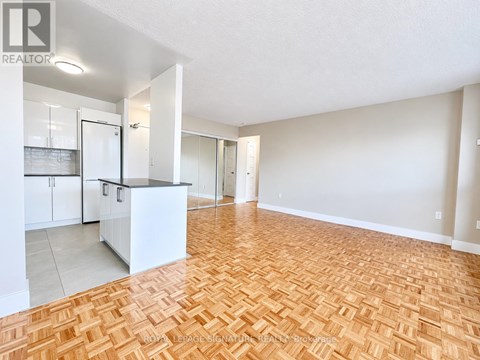 A spacious living room with hardwood flooring and white walls.