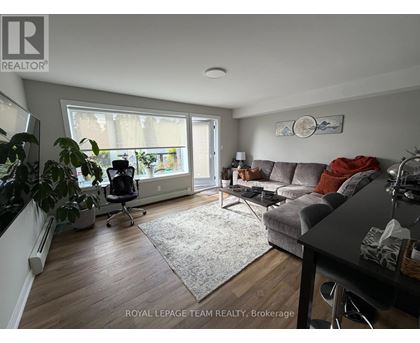 A living room with a grey couch and a large window.