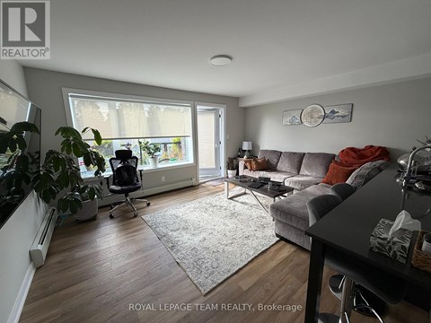 A living room with a grey couch and a large window.