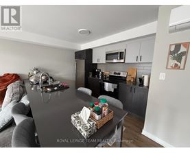 A kitchen with a black countertop and a grey couch.