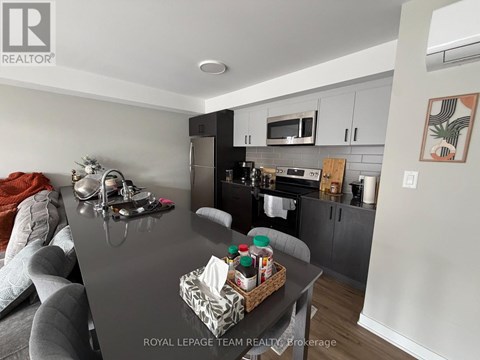 A kitchen with a black countertop and a grey couch.