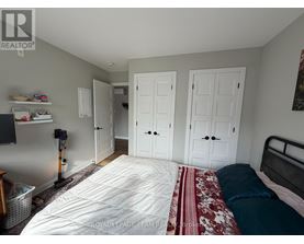 A bedroom with a bed, two closets, and a vacuum cleaner.