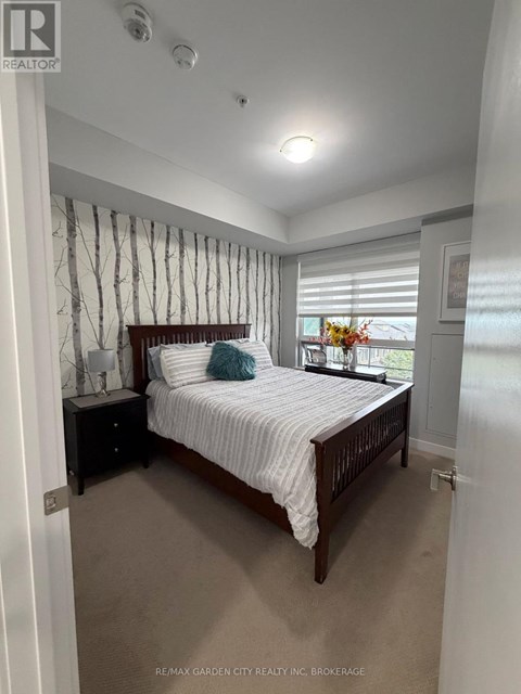 A bedroom with a bed, nightstand, and window with blinds.