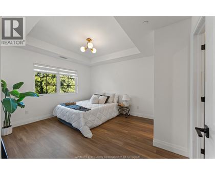 A bedroom with a bed, a plant, and a window.