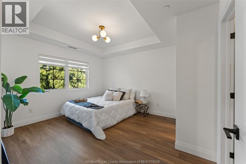 A bedroom with a bed, a plant, and a window.