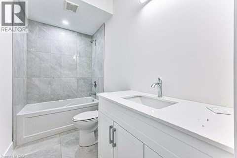 A white bathroom with a tub, toilet and sink.