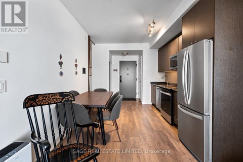 A kitchen with a table and chairs in the foreground and a refrigerator in the background.