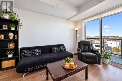 A living room with a black couch, a wooden coffee table, and a large window overlooking the city.