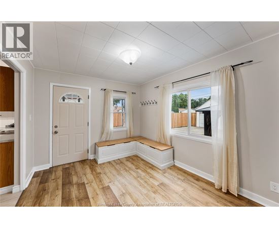 A well-lit room with wooden floors and white walls.