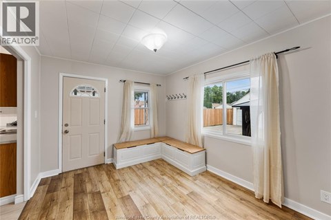 A well-lit room with wooden floors and white walls.