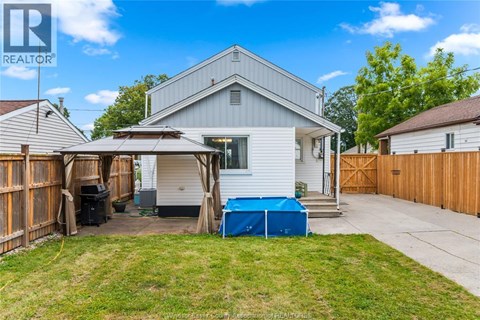 A house with a blue tarp covering a pool in the backyard.