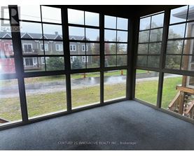 A room with a view of a grassy area and houses through large windows.