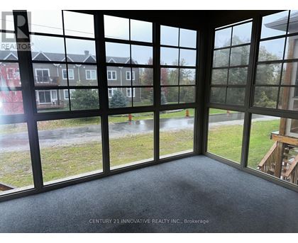 A room with a view of a grassy area and houses through large windows.