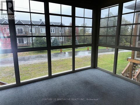 A room with a view of a grassy area and houses through large windows.
