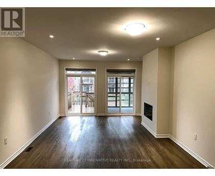 A spacious room with wooden floors and a fireplace.