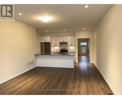 A spacious kitchen with white cabinets and a wooden floor.