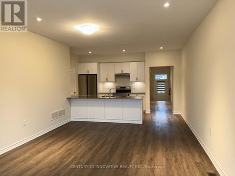 A spacious kitchen with white cabinets and a wooden floor.