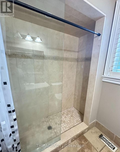 A shower area with a glass door and a tiled floor.