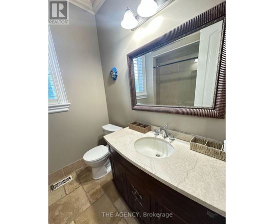 A bathroom with a toilet, sink and mirror.
