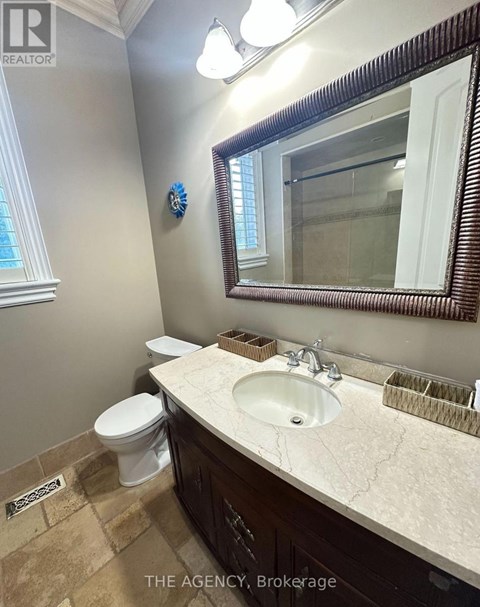 A bathroom with a toilet, sink and mirror.