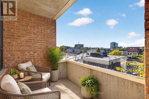 A balcony with a table and chairs overlooking a cityscape.