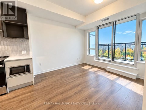 A spacious room with a stove and a window overlooking a balcony.