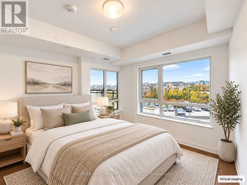 A bedroom with a large bed and a view of a parking lot through the window.