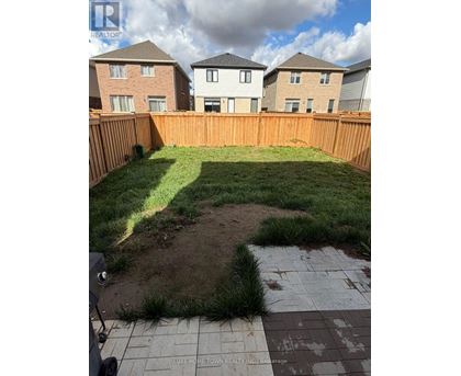 A backyard with a wooden fence and a small patch of dirt in the middle.