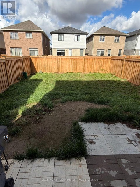 A backyard with a wooden fence and a small patch of dirt in the middle.
