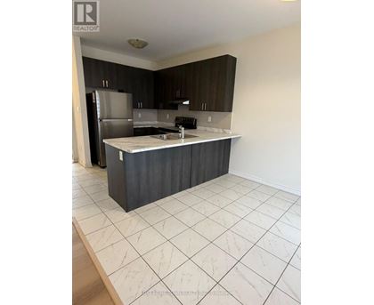 A kitchen with a refrigerator, sink, and cabinets.