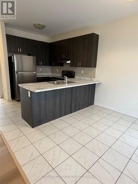 A kitchen with a refrigerator, sink, and cabinets.