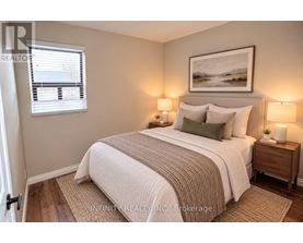 A bedroom with a bed, two lamps, and a painting on the wall.