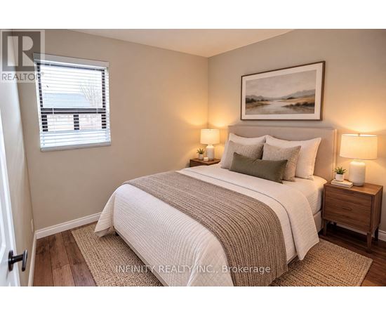 A bedroom with a bed, two lamps, and a painting on the wall.