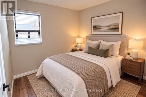 A bedroom with a bed, two lamps, and a painting on the wall.