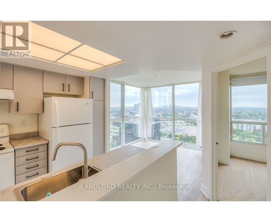 A kitchen with white appliances and a view of the city.