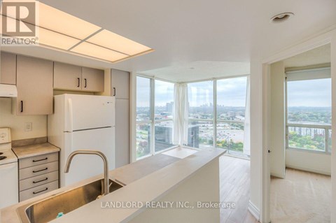 A kitchen with white appliances and a view of the city.