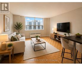 A living room with a couch, a coffee table, a television, and a window with a view of a cityscape.